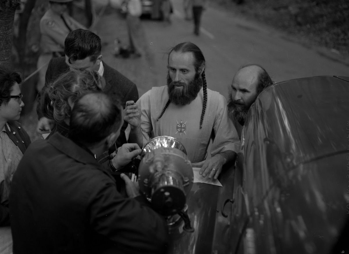 Bishop Asaiah talks with police and reporters outside the ruins of the headquarters of the Fountain of the World cult following a bomb attack by two former members, 11 December 1958. The Regents of the University of California (CC BY 4.0)
